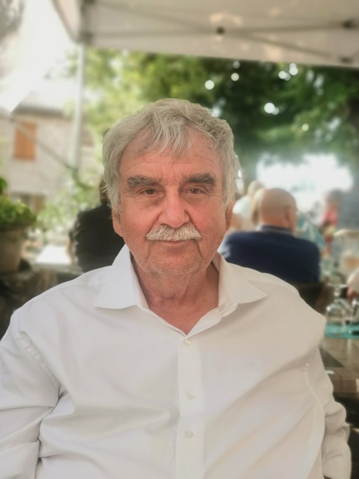 Henning Köster, ein älterer, weißer Mann mit grauen Haaren und weißem Hemd im Porträt.
